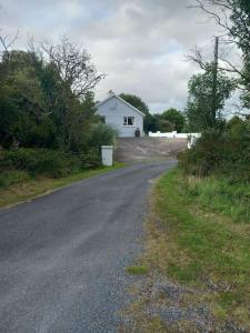 多尼戈尔Spacious Cottage in Meenaleck near Gweedore County Donegal的一条空的路,后面有一座白色的房子