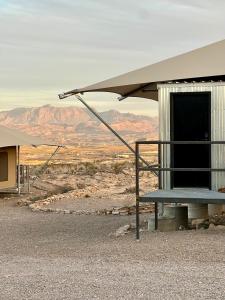 特灵瓜Camp Elena - Luxury Tents Minutes from Big Bend and Restaurants的沙漠中一座有遮阳篷和长凳的建筑
