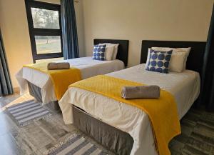 卢萨卡Chuumba Villas的配有两张黄色和蓝色枕头的床铺