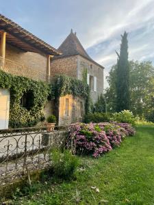 DuravelChâteau la Gineste - Castle and Vineyard的院子里的石头房子,鲜花盛开