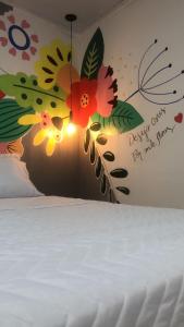 库亚巴Top Coliving I的卧室配有白色的床铺,墙上绘有鲜花