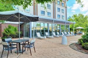 巴吞鲁日巴吞鲁日希尔顿逸林酒店的庭院配有椅子和桌子及遮阳伞