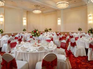 伦敦希尔顿伦敦帕丁顿酒店的宴会厅设有白色的桌子和红色的弓