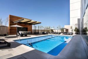 阿瓜斯卡连特斯Hilton Garden Inn Aguascalientes的一座带椅子的游泳池以及一座建筑