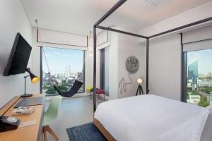 迪拜Canopy by Hilton Dubai Al Seef的卧室配有白色的床、书桌和窗户。