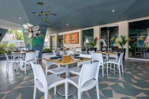 圣胡安Condado Palm Inn San Juan, Tapestry Collection by Hilton的餐厅设有白色的椅子和桌子以及窗户。