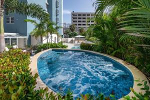 圣胡安Condado Palm Inn San Juan, Tapestry Collection by Hilton的一座种植了棕榈树和建筑的大型蓝色游泳池