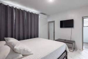阿瓜迪亚Ramey Cir D, near airport, beaches W/KING Bed.的一间白色卧室,配有床和电视