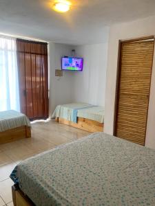 索里托斯La Tablita的一间卧室设有两张床,墙上配有电视。