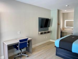 休斯顿Blue Star Inn的一间卧室配有书桌、一张床和电视。