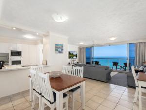 黄金海岸Peninsula 21b的厨房以及带桌椅的起居室。