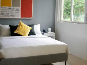 KababaeEmerald Manor Hotel的卧室配有带枕头的床铺和窗户。
