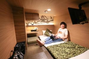 大阪HOTEL Cargo Shinsaibashi的坐在床上的女士,手提电脑