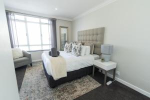 伊丽莎白港Tivoli Luxury Beach Apartment的卧室配有床、椅子和窗户。