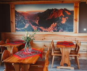 布科维纳-塔钱斯卡Bukowiańska Ostoja的一间设有两张桌子和山壁画的用餐室