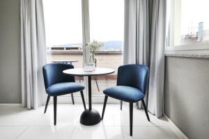 苏黎世numa I Turi Apartments的窗户间里一张桌子和两把蓝色椅子