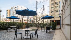 名古屋名古屋金山名铁旅馆的一个带桌椅和蓝伞的庭院