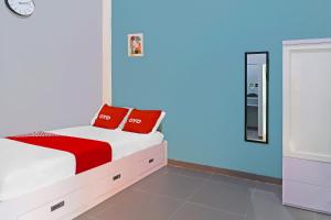 占碑市OYO Life 92691 Mc Kost Syariah的一间卧室配有一张带红色枕头的床