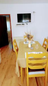 弗济内Apartman Barbara的黄色的餐桌、椅子和电视