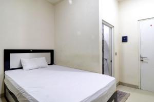 占碑市OYO Life 92707 D-akomiba Residence的一间卧室配有一张带白色床单的床和一扇窗户。