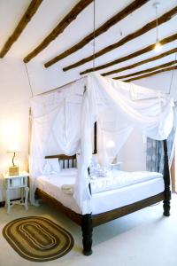 马林迪Met Beach Resort Malindi的卧室配有一张带地毯的天蓬床