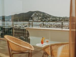 圣埃乌拉利亚Aguas de Ibiza Grand Luxe Hotel - Small Luxury Hotel of the World的阳台配有两把椅子和一张带葡萄酒玻璃的桌子。