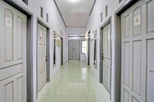 外南梦OYO Life 92937 Kost Putri Sarkara Syariah的走廊设有白色门,铺有白色瓷砖地板