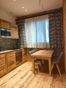 布勒伊-切尔维尼亚Fior di Roccia Apartments的厨房配有木桌、椅子和窗户。