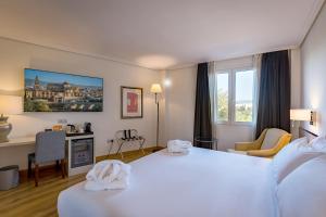 科尔多瓦Hesperia Córdoba的酒店客房设有一张白色大床和一张书桌