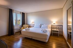 科尔多瓦Hesperia Córdoba的酒店客房设有一张白色大床和椅子