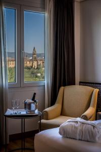 科尔多瓦Hesperia Córdoba的酒店客房设有椅子、桌子和窗户。