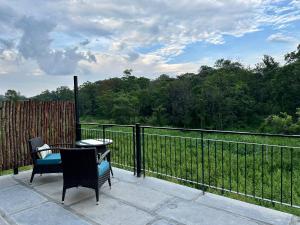 SrimangalaMachaan Wilderness Lodge Nagarahole的庭院设有两把椅子、一张桌子和围栏
