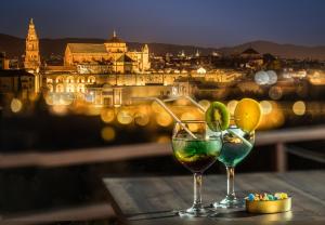 科尔多瓦Hesperia Córdoba的一张桌子上放两杯葡萄酒,享有城市美景