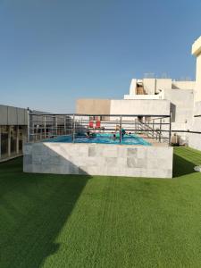 吉达Paradise Inn Jeddah Hotel的一座绿色草丛建筑顶部的游泳池