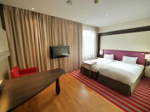 华沙华沙美居大酒店的酒店客房设有一张大床和一张红色椅子。