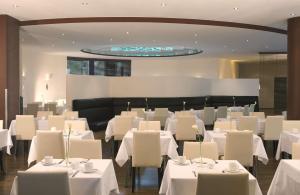 德累斯顿德累斯顿新城NH酒店的用餐室配有白色的桌子和白色的椅子