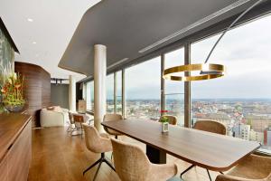 慕尼黑NH Collection München Bavaria的一间带桌椅和大窗户的用餐室