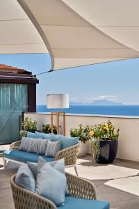 那不勒斯The Britannique Hotel Naples, Curio Collection By Hilton的一个带沙发和椅子的庭院和大海
