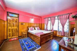 GhumGRG Tharbaling Homestay Darjeeling的一间卧室配有一张粉红色墙壁的床