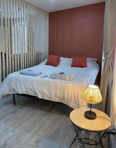 马诺斯克Appartement loft terracotta的一张带红色枕头的床和一张带台灯的桌子