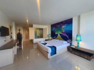 清迈太平洋时尚酒店的卧室配有一张大床,墙上挂有绘画作品