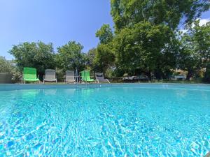 卢马罕La ferme d'Andréa au milieu des vignes à 3min à pied du centre piscine chauffée climatisation的一个带椅子和树木的大型游泳池