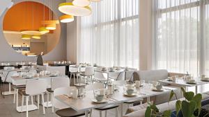 诺德林根Hey Lou Hotel Nördlingen的餐厅设有白色的桌椅和窗户。