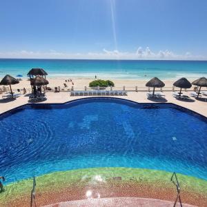 坎昆Ocean front Villa Marlin, best location in hotel zone #109的海滩旁的游泳池,配有遮阳伞