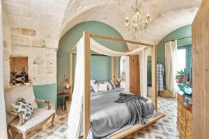 法萨诺Bambarone La Masseria的一间卧室配有一张天蓬床和一把椅子