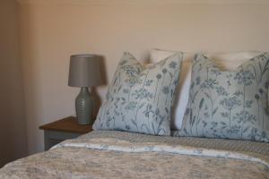 斯托昂泽沃尔德Beautiful Cottage in the Heart of Stow on the Wold的一张带蓝色和白色枕头的床和一盏灯