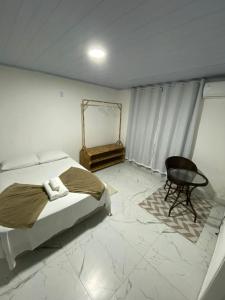 曼加拉蒂巴Pousada Lisamar的一间卧室配有一张床、一把椅子和一张桌子