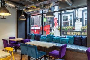 利物浦Kabannas Liverpool的餐厅在窗户前设有紫色椅子和蓝色沙发