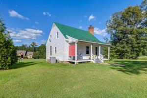 中洛锡安Tranquil Cottage in Virginia Countryside with Pond!的田野上带绿色屋顶的白色房子