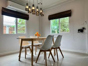 闵埔丽Happy home บ้านกว้าง ได้ทั้งหลัง ไวไฟฟรี1000Mbps ใกล้สนามบินสุวรรณภูมิ的一间带木桌和白色椅子的用餐室